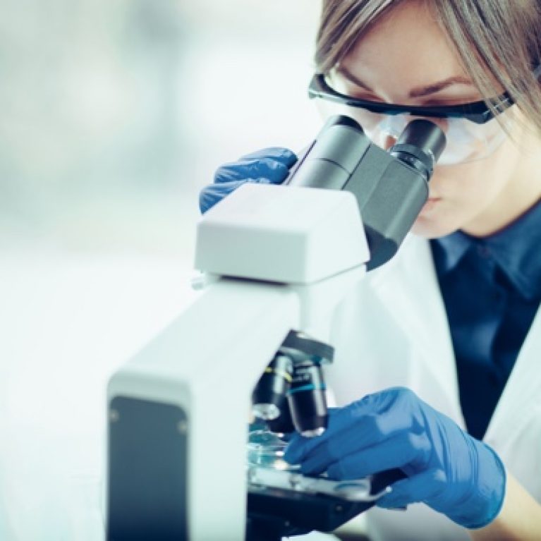 Researcher looking at a specimen in a microscope